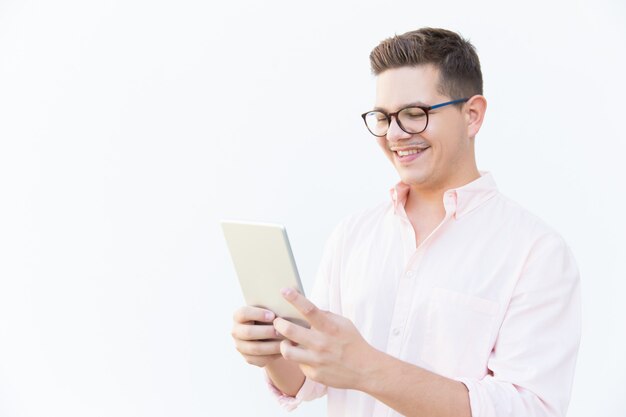 Cheerful guy in eyeglasses watching content on tablet