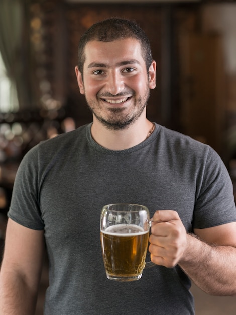 Cheerful guy with beer in bar