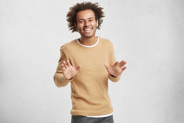 Cheerful handsome African American male has crisp hair, dressed casually