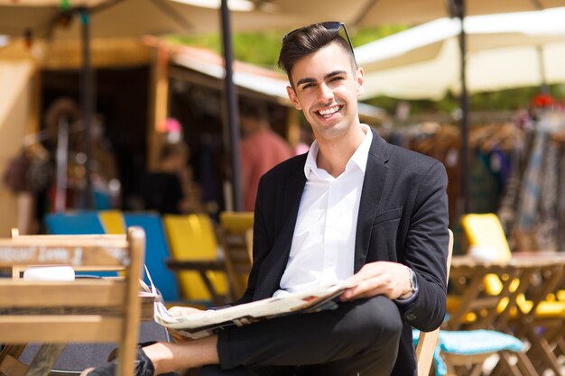 Cheerful handsome businessman resting outside cafe