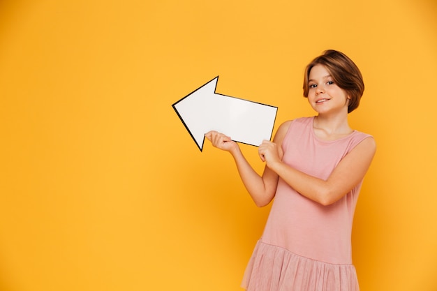 Cheerful handsome girl holding arrow left and looking camera