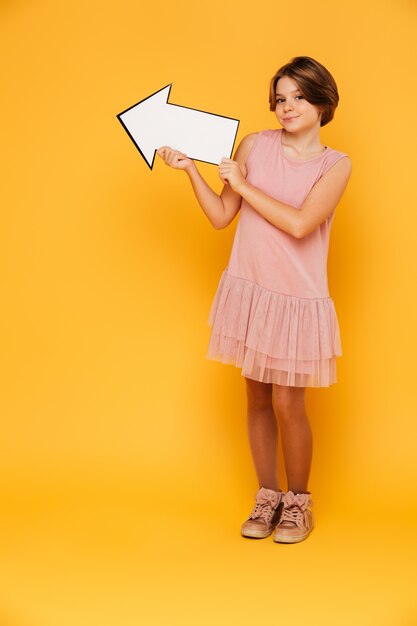 Cheerful handsome girl holding arrow left and looking camera