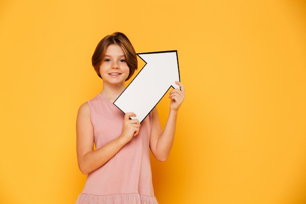 Cheerful handsome girl holding arrow left and looking camera