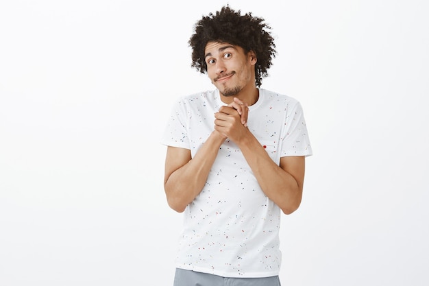 Cheerful handsome man clasp hands and looking hopeful, begging for something