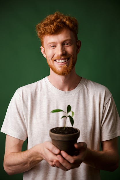 Веселый красавец рыжий бородатый молодой битник, держа в горшке растение