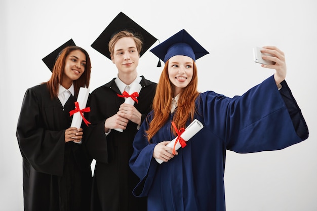 Cheerful happy graduates fooling smiling making selfie.