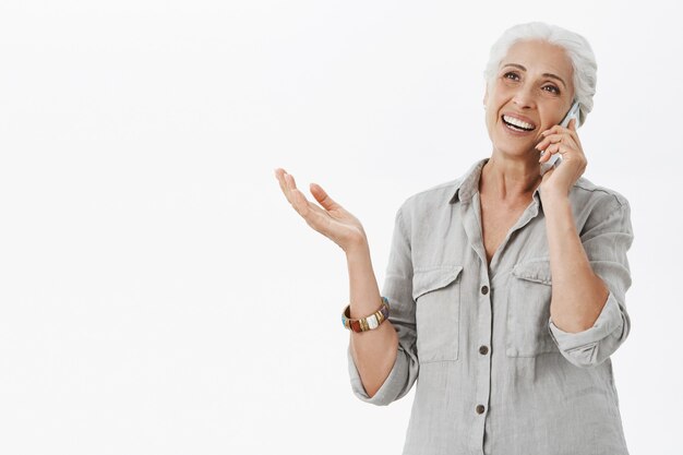 쾌활한 행복 할머니 휴대 전화로 이야기하고 웃고