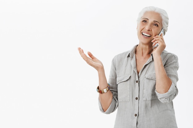 Cheerful happy grandmother talking on mobile phone and smiling