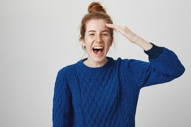 Cheerful happy smiling redhead girl saluting