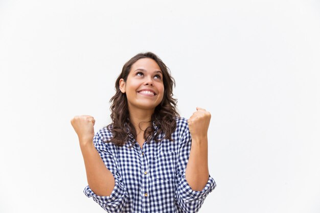 Cheerful happy woman making winner gesture and looking up