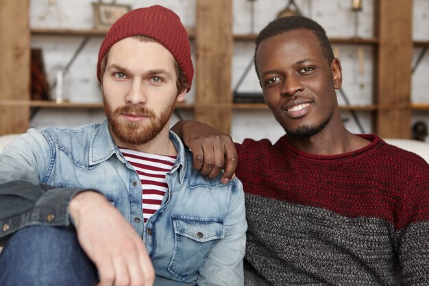 Cheerful happy young Caucasian and African friends wearing stylish clothing talking