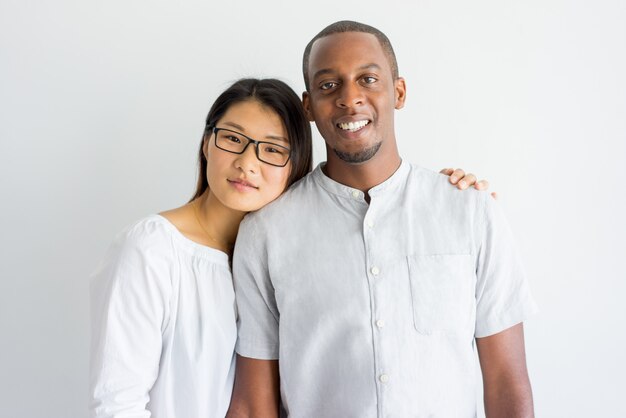 Cheerful jolly young interracial couple looking at camera. 