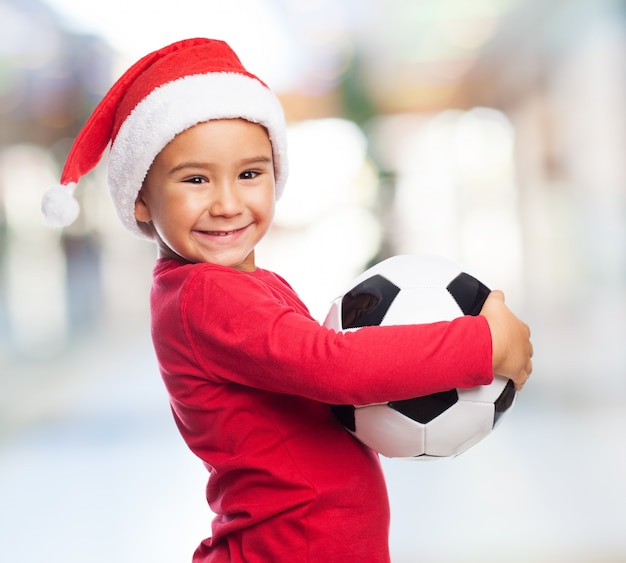 Cheerful kid holding his ball with blurred background
