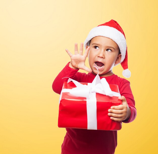 Cheerful kid holding a red gift box