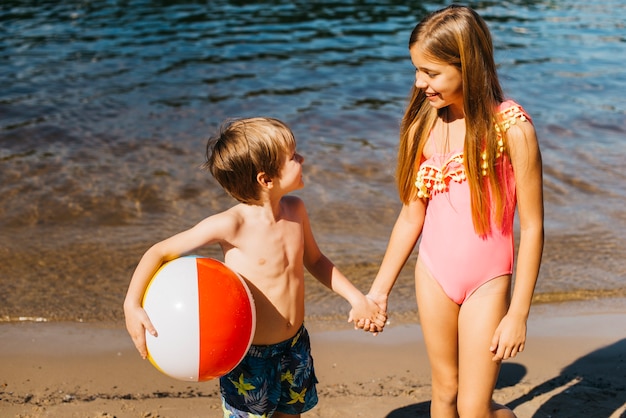 Cheerful kids looking at each other on shore