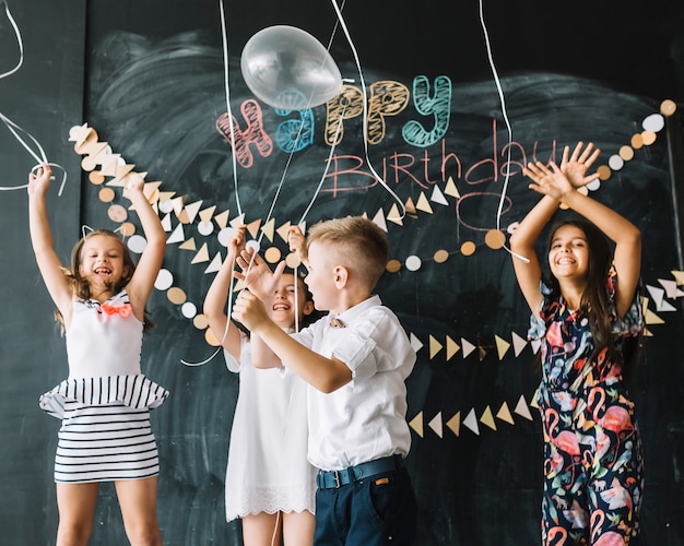 Cheerful kids releasing balloons on birthday party