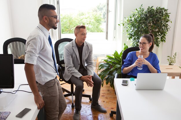 Cheerful lady boss talking to employees