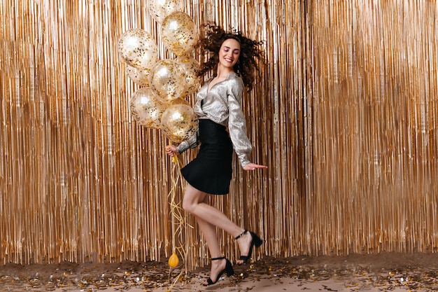無料写真 ゴールドの背景にジャンプするシルバーのブラウスで陽気な女性