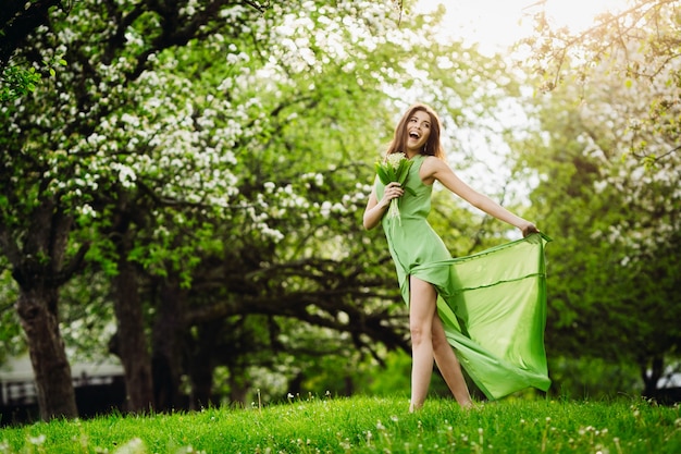 녹색 정원에서 쾌활 한 여자 점프