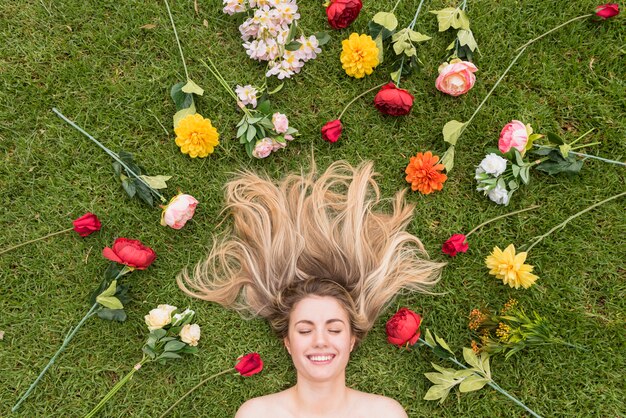 花の間草の上に横たわる陽気な女性