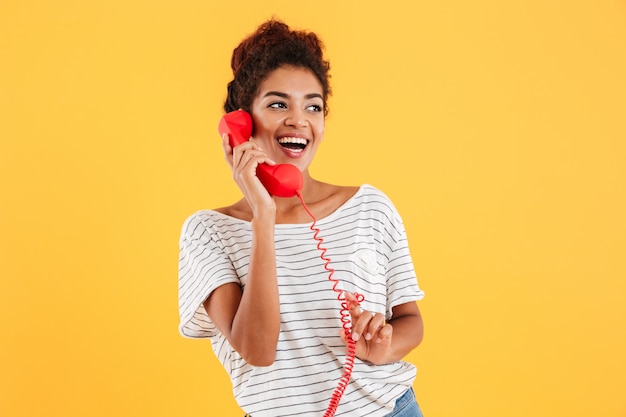 Free photo cheerful lady talking on red telephone and looking aside