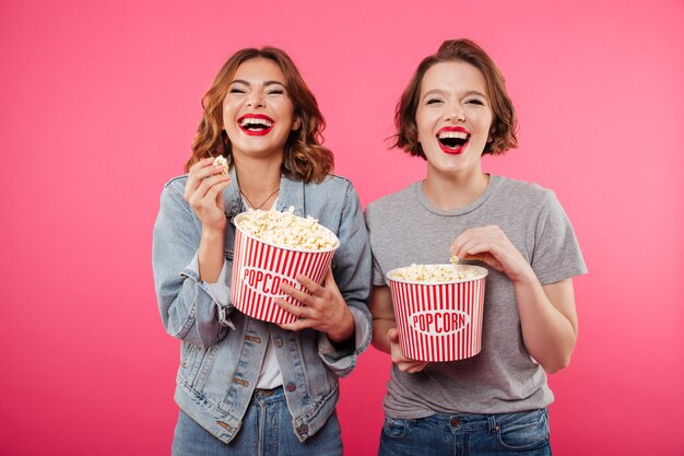 Cheerful laughing women eating popcorn watch film.