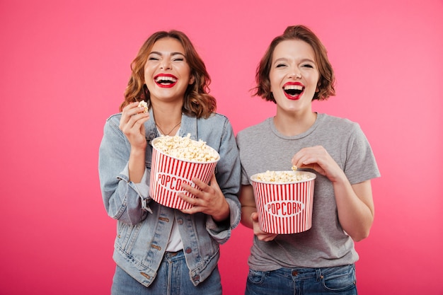 Cheerful laughing women eating popcorn watch film.