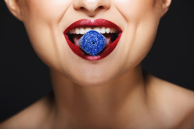 Free photo cheerful lips holding sweeties with teeth.