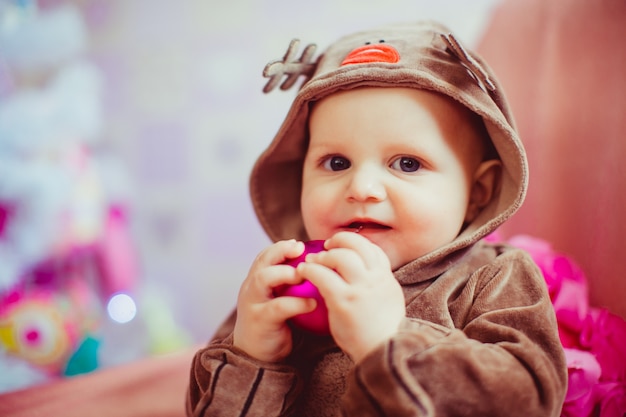 Cheerful little baby boy playing near the Christmas tree