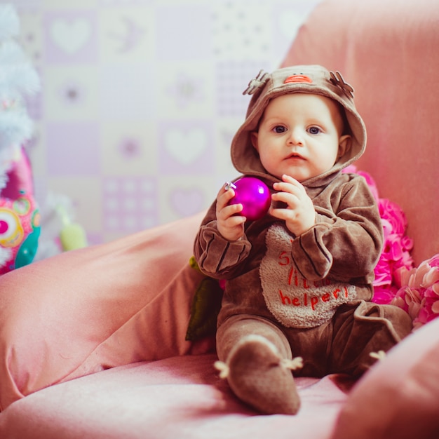 Cheerful little baby boy playing near the Christmas tree