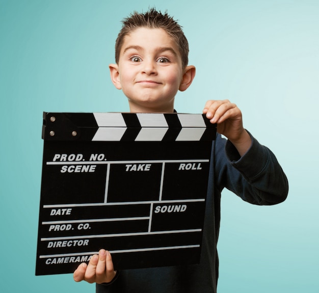 Cheerful little boy playing with a clapperboard