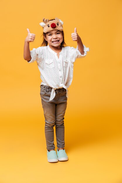 Cheerful little girl child showing thumbs up.