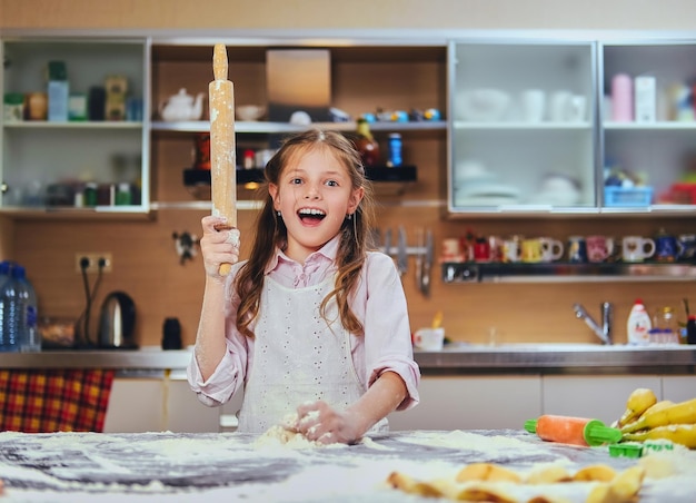 Foto gratuita bambina allegra che cucina pasta in cucina.