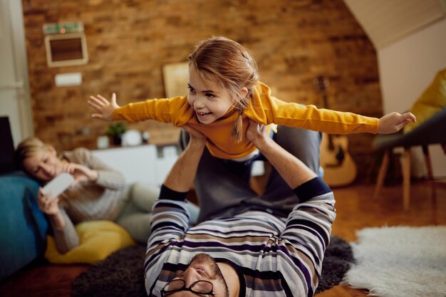 Cheerful little girl having fun while playing with her father at home