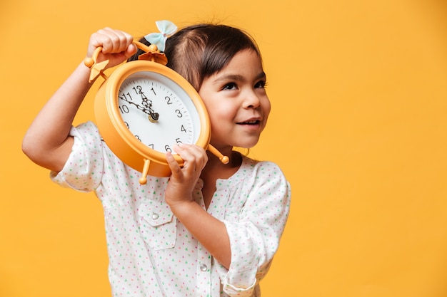 Cheerful little girl holding clock alarm.