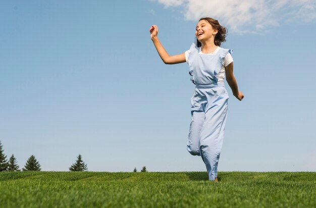 Cheerful little girl running on grass