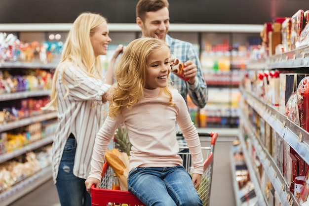 Cheerful little girl sitting on a shopping cart