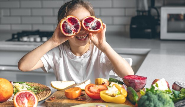 cheerful little girl with oranges in the kitchen interior
