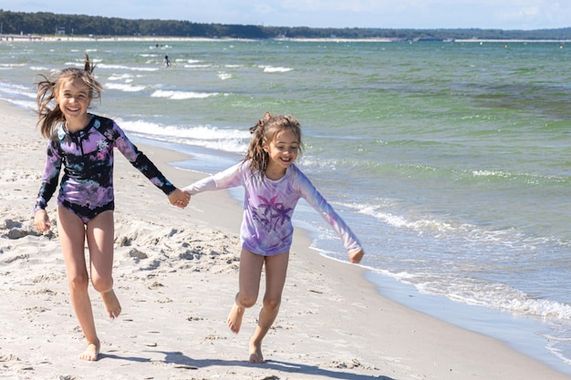 Free photo cheerful little girls sisters play on the seashore