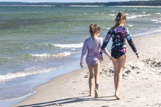 Cheerful little girls sisters play on the seashore