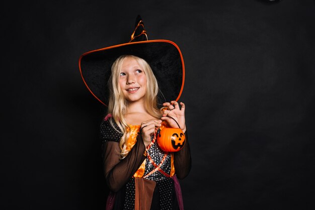 Cheerful little witch with plastic bucket