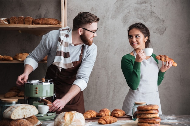 Cheerful loving couple bakers drinking coffee