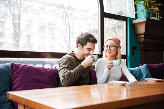 陽気な愛情のあるカップルはカフェに座って、コーヒーを飲みます。