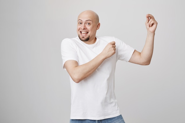 Cheerful lucky bald man dancing happy