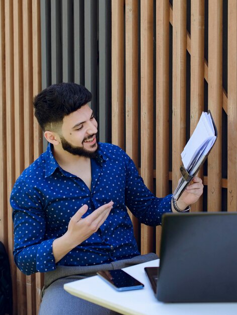 Cheerful male manager checking notebook while sitting at table in cafe