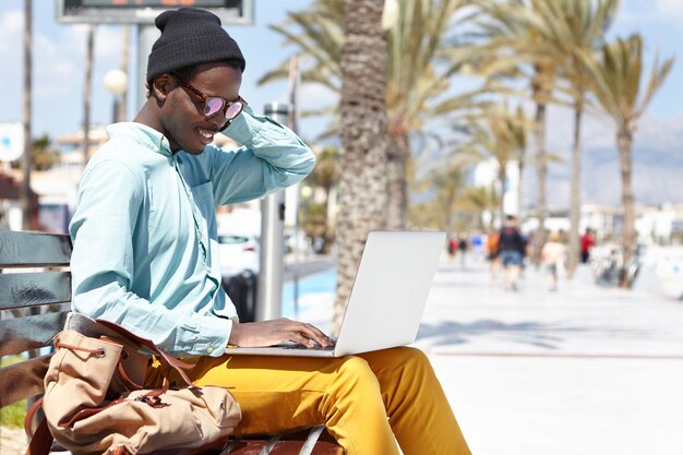 Cheerful male using laptop outdoors