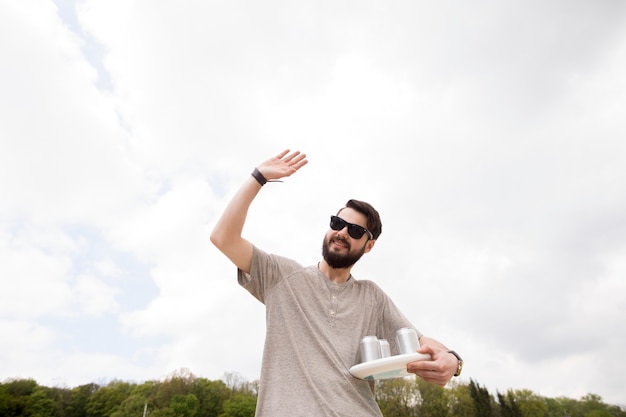 Free photo cheerful male with drinks waving hand