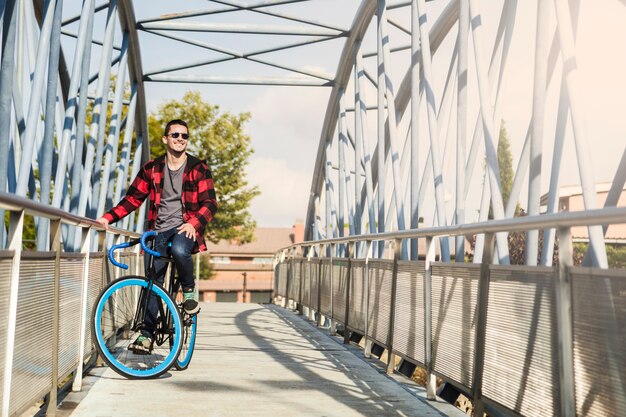 Free photo cheerful man on bicycle on bridge