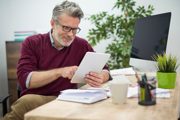 Cheerful man browsing websites on his digital tablet