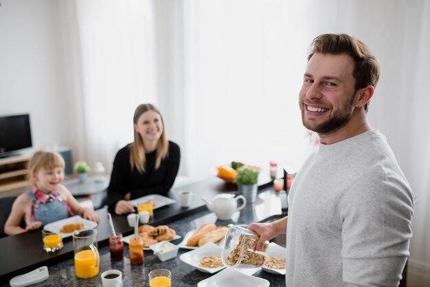 Cheerful man cooking breakfast for family